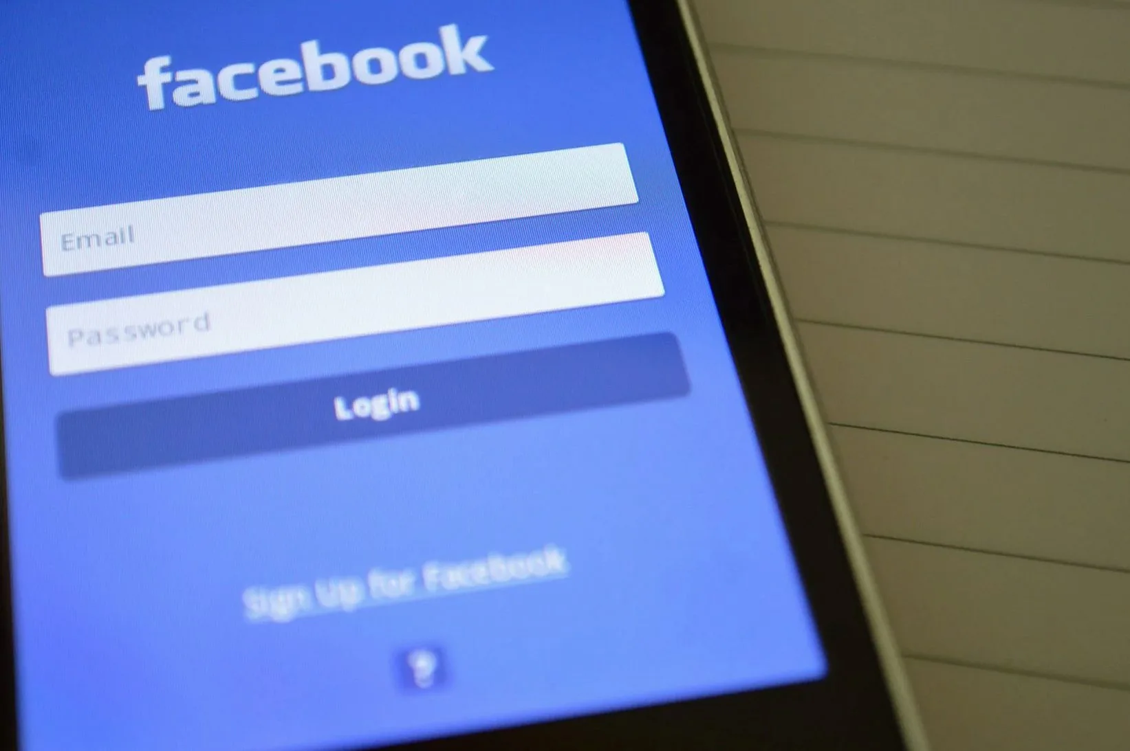 Facebookのログイン画面が表示されたスマートフォン。デジタル接続とソーシャルメディアの利用を象徴しています。